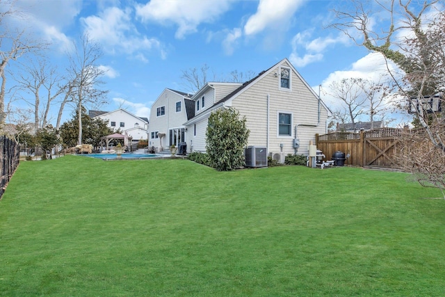 rear view of property with a lawn, a gazebo, central AC unit, a gate, and fence