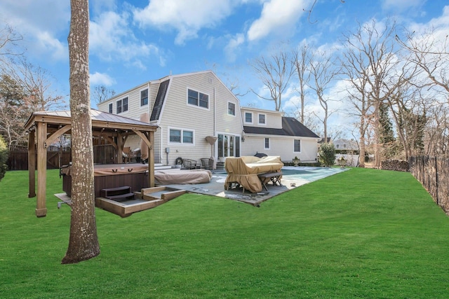 back of property with a lawn, a hot tub, a gambrel roof, a gazebo, and a patio area