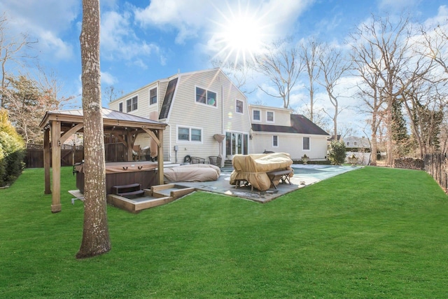 rear view of house featuring a hot tub, a gambrel roof, a fenced backyard, a gazebo, and a patio area