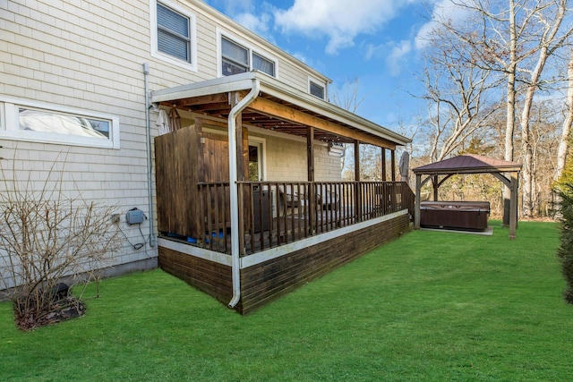 rear view of property featuring a yard, a hot tub, and a gazebo