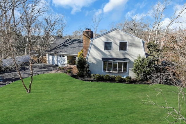 view of front of house featuring a garage, a gambrel roof, a chimney, aphalt driveway, and a front yard