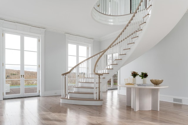 stairs featuring hardwood / wood-style flooring, ornamental molding, plenty of natural light, and a high ceiling