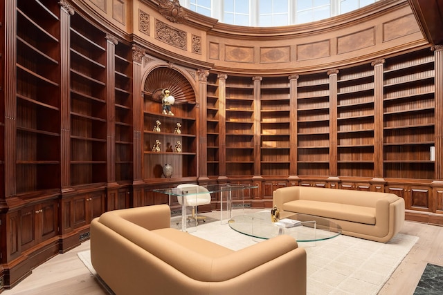 wine room featuring a towering ceiling, light hardwood / wood-style flooring, built in shelves, and wood walls