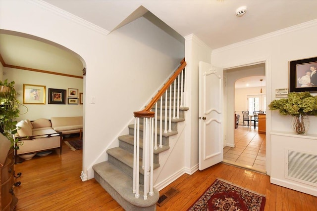 stairway featuring crown molding and hardwood / wood-style flooring