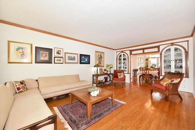 living room with a notable chandelier, ornamental molding, and hardwood / wood-style floors