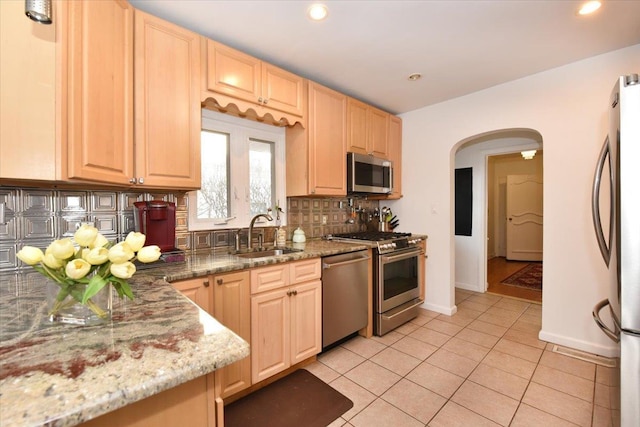 kitchen with appliances with stainless steel finishes, light brown cabinets, decorative backsplash, sink, and light tile patterned flooring