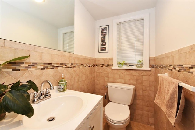 bathroom with toilet, tile walls, and vanity