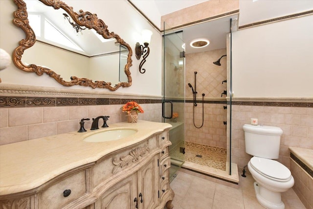 bathroom with toilet, vanity, tile walls, tile patterned floors, and a shower with door