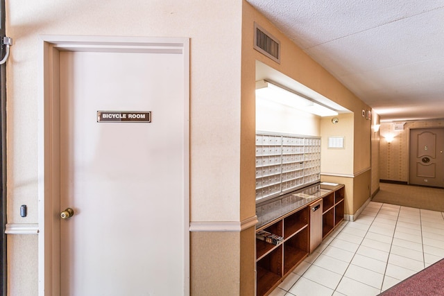 corridor with mail boxes, a textured ceiling, and light tile patterned floors