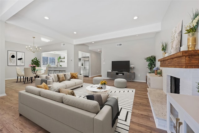 living room featuring light hardwood / wood-style flooring, beamed ceiling, and an inviting chandelier