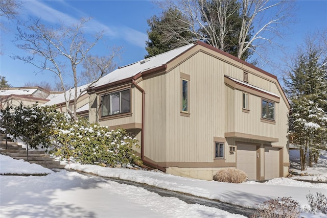 snow covered property with a garage