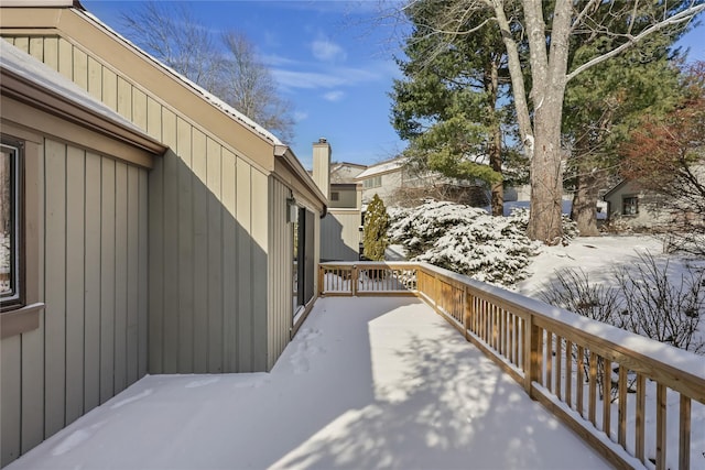 snow covered patio with a wooden deck