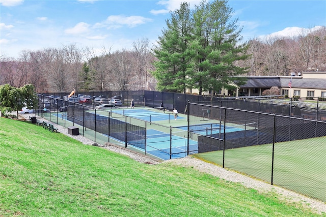 view of tennis court with a yard and fence