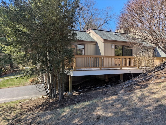 exterior space with a shingled roof, a chimney, and a deck