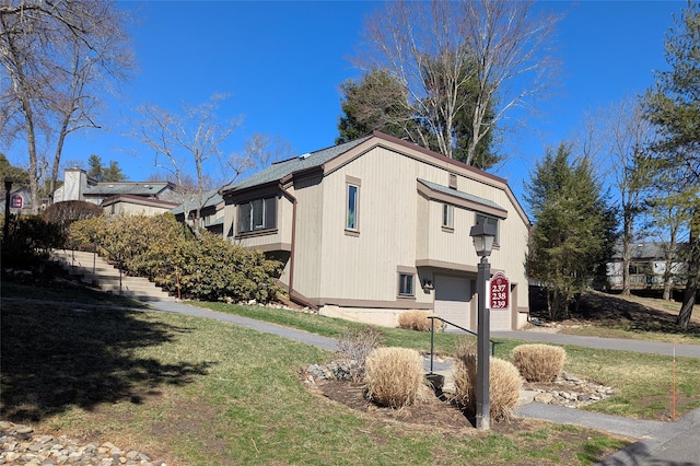 view of property exterior with an attached garage and a yard