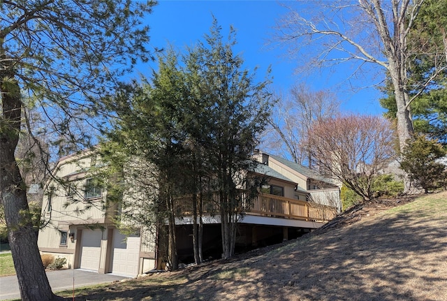 exterior space with an attached garage, driveway, and a deck