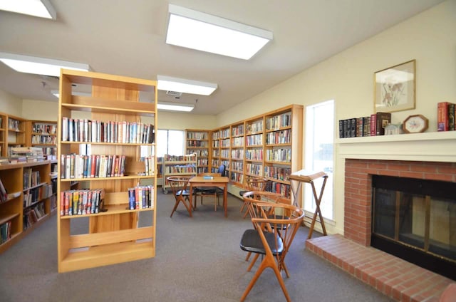 living area featuring carpet floors, bookshelves, and a fireplace