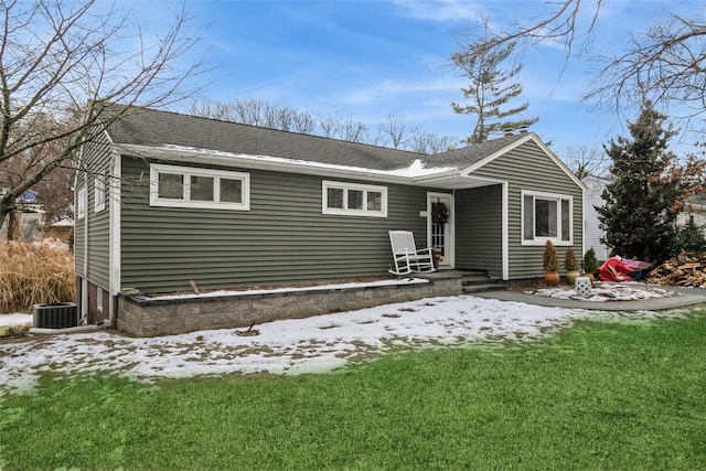 snow covered property with central AC and a lawn