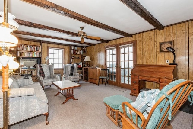 carpeted living room featuring ceiling fan, french doors, beamed ceiling, and wooden walls