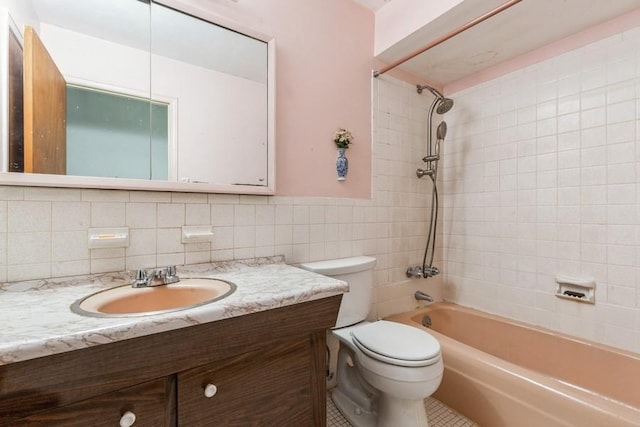 full bathroom with toilet, tiled shower / bath, tile walls, tile patterned floors, and vanity