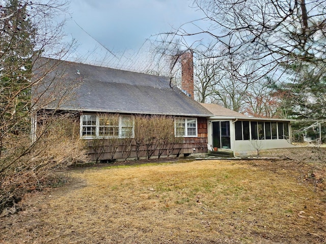 back of property with a lawn and a sunroom