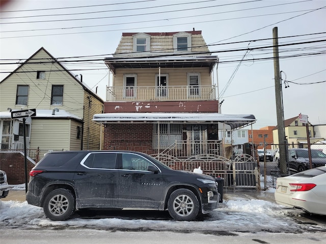 view of front of home featuring covered porch, mansard roof, and fence