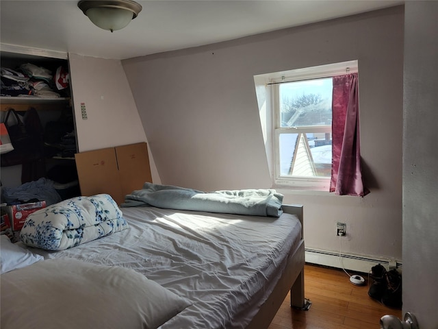 bedroom with a baseboard radiator, a closet, and wood finished floors