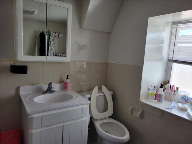 bathroom with vanity, toilet, and tile walls