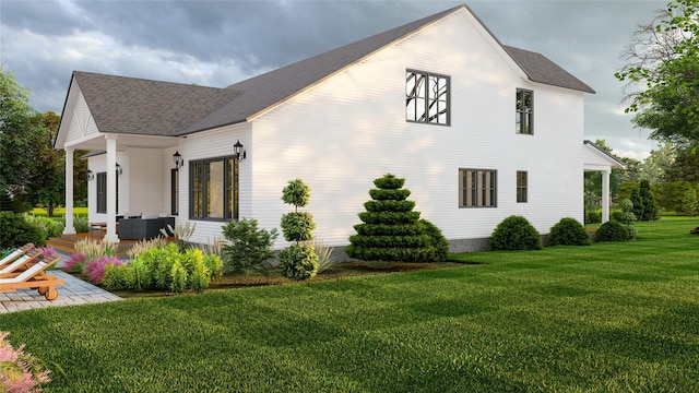 view of side of home with a patio, a lawn, and roof with shingles