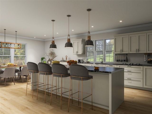 kitchen with dark countertops, light wood-style flooring, a kitchen breakfast bar, a center island, and decorative light fixtures