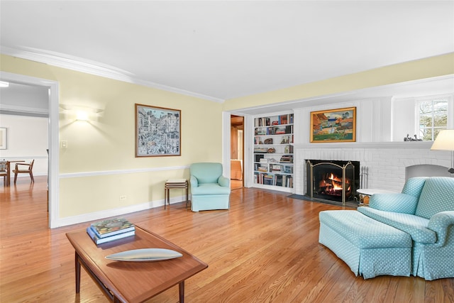 living room with crown molding, a brick fireplace, and light wood finished floors