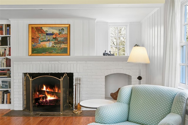 sitting room featuring a brick fireplace and wood finished floors