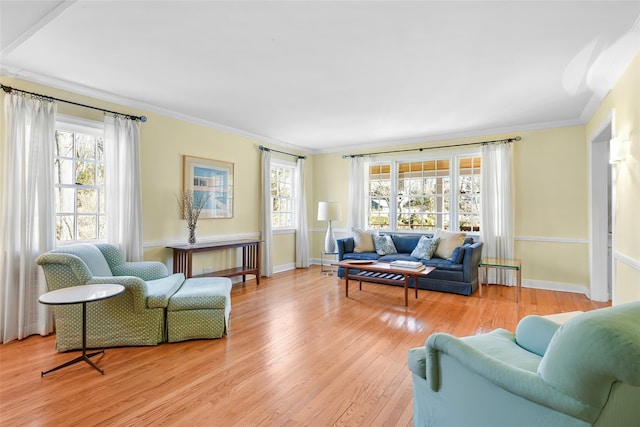 living area featuring plenty of natural light, baseboards, light wood-style floors, and ornamental molding