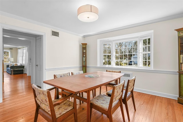 dining area with crown molding, baseboards, visible vents, and light wood-type flooring