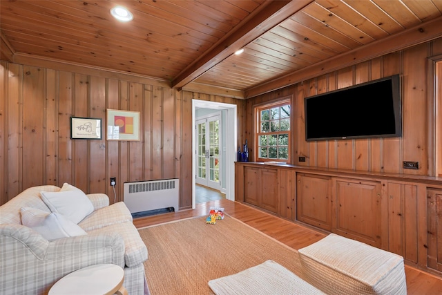 living room featuring wooden walls, radiator heating unit, wood ceiling, beamed ceiling, and light wood-type flooring