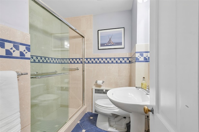 full bath featuring tile patterned flooring, tile walls, toilet, and a shower stall