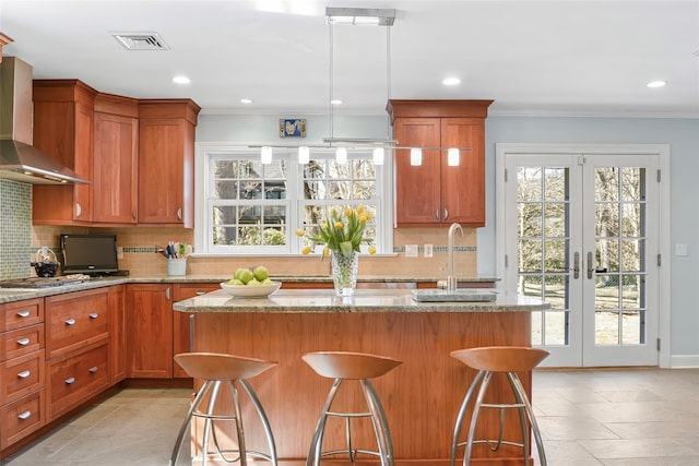 kitchen with visible vents, ornamental molding, french doors, wall chimney exhaust hood, and a sink