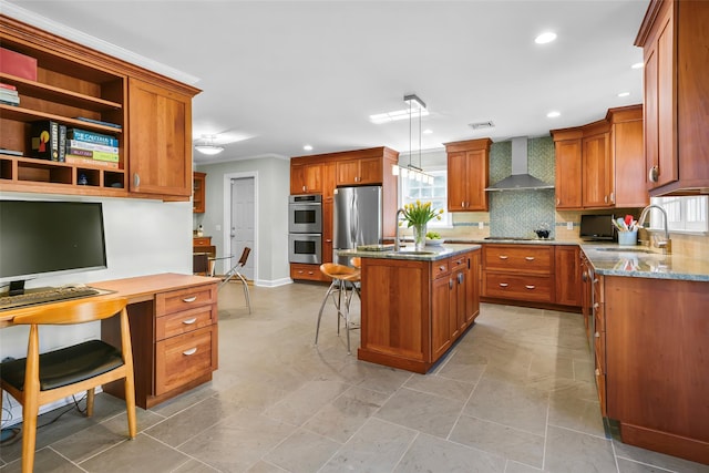 kitchen with wall chimney range hood, a kitchen breakfast bar, brown cabinetry, stainless steel appliances, and a sink