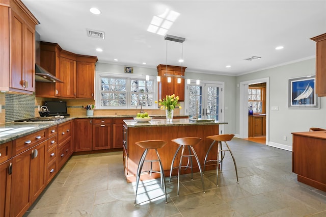 kitchen with visible vents, stone counters, ornamental molding, tasteful backsplash, and a center island