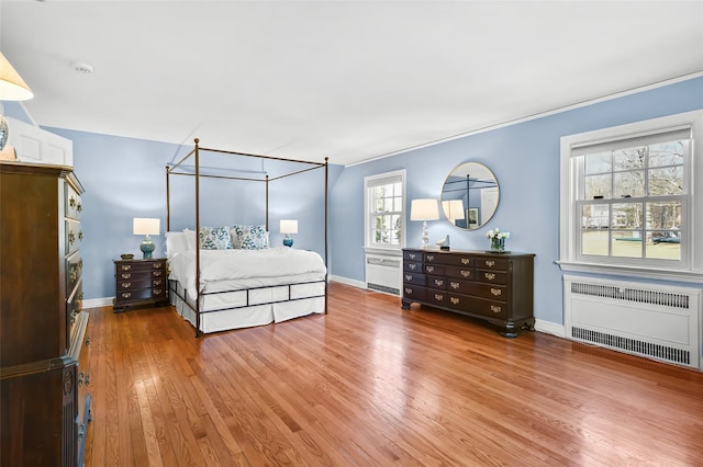 bedroom featuring radiator heating unit, baseboards, and light wood finished floors