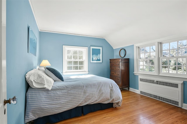 bedroom with baseboards, radiator, wood finished floors, and vaulted ceiling