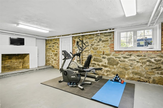 exercise area with a fireplace with raised hearth and a textured ceiling