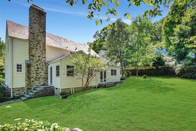 rear view of house with a yard, fence, and a chimney