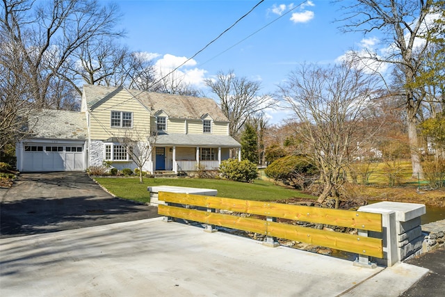 view of front of house featuring aphalt driveway, a front yard, covered porch, and an attached garage