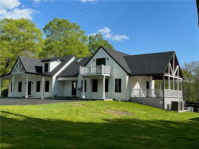 rear view of property featuring a balcony, a yard, and covered porch