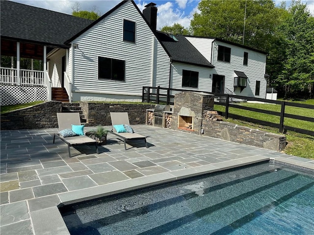 rear view of house featuring a patio and an outdoor stone fireplace