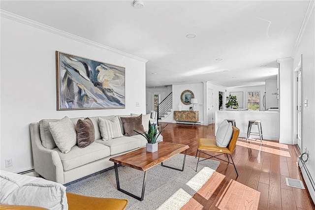 living room with hardwood / wood-style flooring, ornamental molding, and a baseboard heating unit