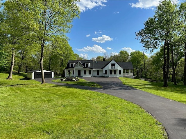 view of front of property featuring a garage, an outdoor structure, and a front lawn