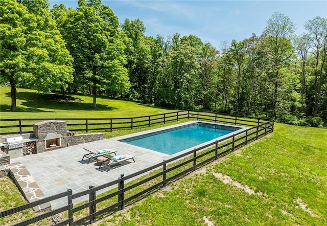 view of swimming pool with a yard, an outdoor stone fireplace, and a patio area