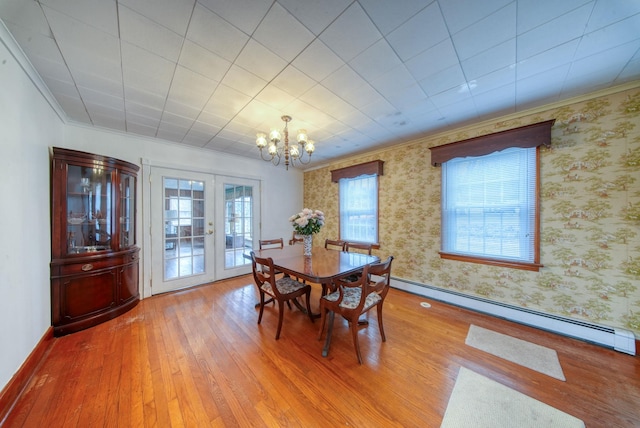 dining room with a notable chandelier, hardwood / wood-style floors, a baseboard heating unit, french doors, and ornamental molding